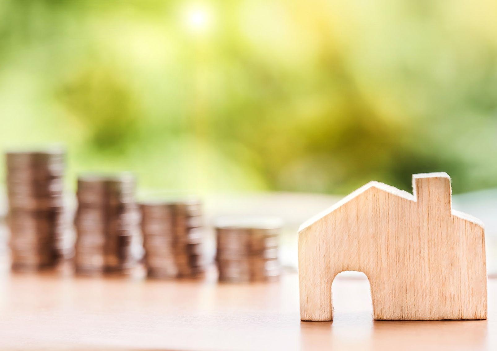 stack of coins beside a house cutout